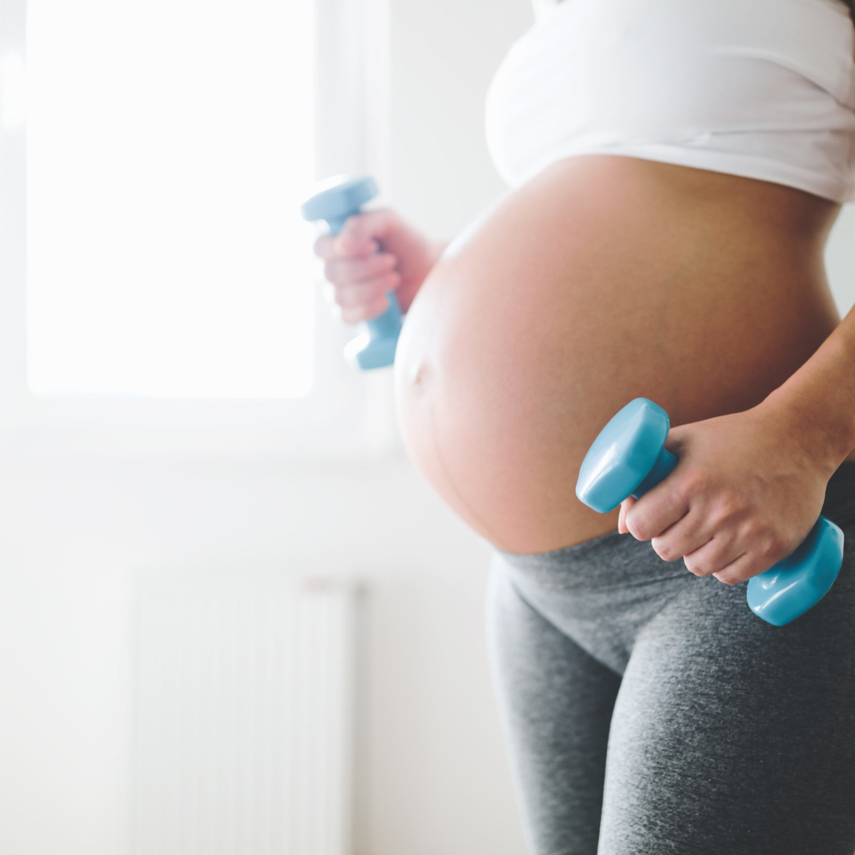 pregnant women exercising holding blue weights