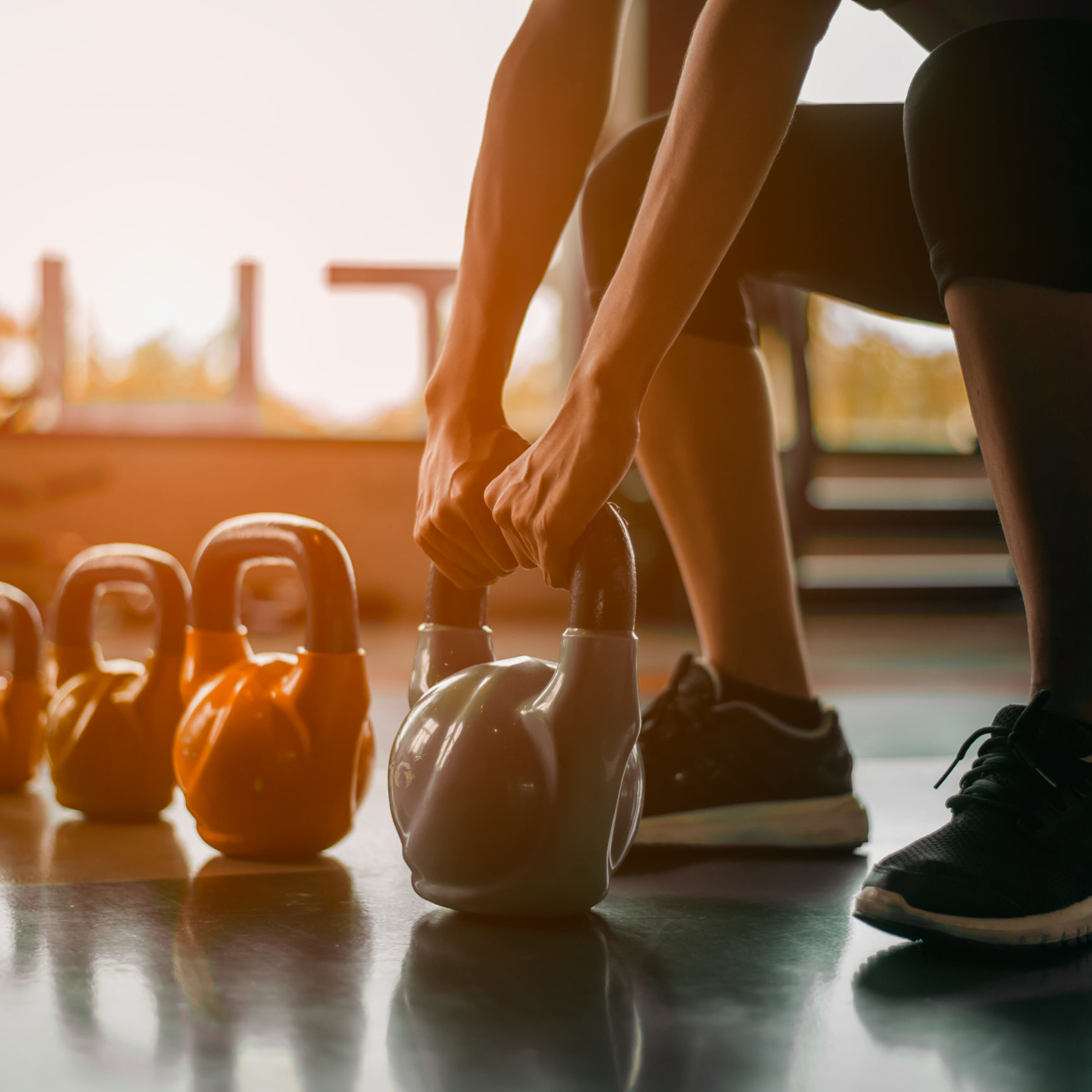 Women in gym picking up weights to exercise in sunrise